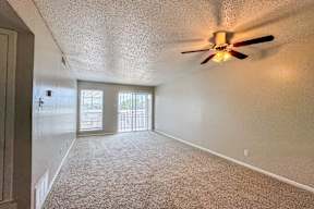 A room with a ceiling fan and carpeted floor.