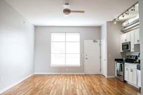 A kitchen with white cabinets and a wooden floor.