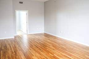 A room with a wooden floor and a doorway leading to another room.