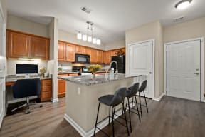 Riverstone - Open Kitchen with Granite Countertops, Shaker Style Cabinetry with Brushed Nickel Hardware Pulls, and Wood Plank Flooring