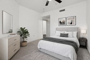A bedroom with a large bed, a dresser, and a ceiling fan.
