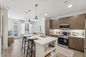 an open kitchen and dining area with a white island and wooden cabinets