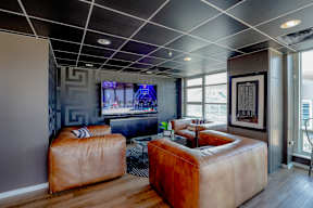 A living room with a brown leather sofa and a television.