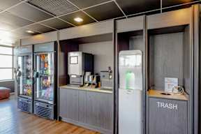 A room with a trash bin and a fridge.