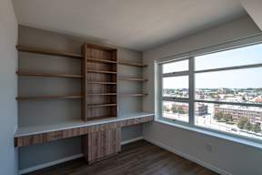 A room with a window overlooking a cityscape and a shelving unit.