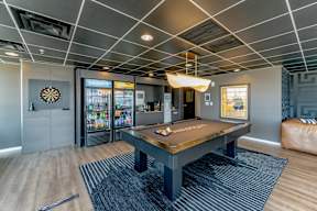 A room with a pool table and a dartboard on the wall.