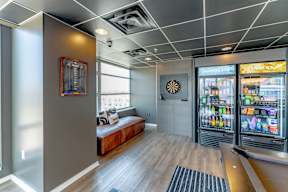 A room with a fridge and a dart board on the wall.