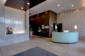 A reception area with a white counter and a black chair.