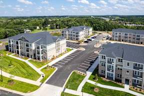 A large, modern apartment complex with a spacious parking lot and well-manicured lawns.