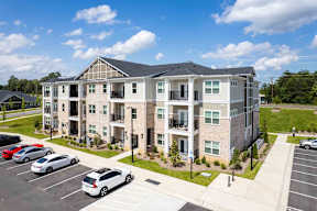 A large apartment complex with a parking lot in front.