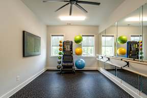 A room with a mirror, a fan, and exercise equipment.