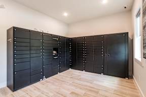 A room with a row of black cupboards and wooden flooring.