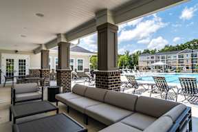 A patio with a sofa, chairs and a pool.