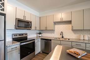 A modern kitchen with a stainless steel refrigerator, microwave, oven, and dishwasher.
