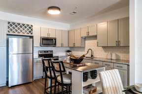 A kitchen with a refrigerator, microwave, oven, and sink.