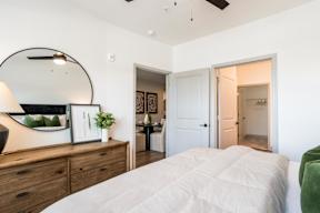 A bedroom with a large bed and a dresser with a mirror above it.
