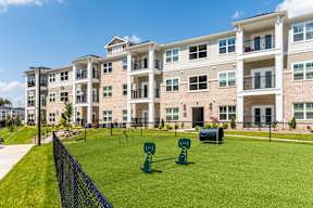 A large apartment complex with a green lawn and playground equipment.