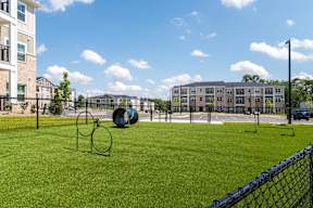 A playground with a green swing set and a blue fence.
