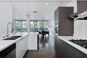 A modern kitchen with dark wood floors and white countertops.
