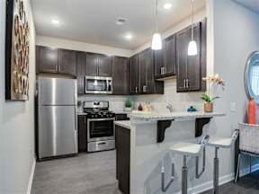 Flemington, NJ, Luxury Apartments - Pavilion at Raritan - A Kitchen with Wood-Style Flooring, Granite Countertops, and Stainless Steel Appliances.