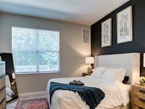 1 Bedroom Luxury Apartments in Flemington, NJ - Pavilion at Raritan - A Bedroom with Carpeting, Two Bedside Tables with Lamps, and a Large Window with Blinds.