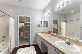 A bathroom with a sink, mirror, and bathtub.