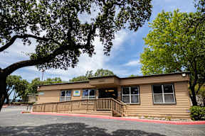A small building with a porch is surrounded by trees.
