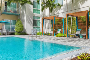 a swimming pool in front of a building with palm trees