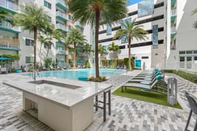 a swimming pool with a table and chairs in front of an apartment building