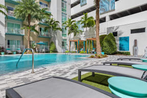 a swimming pool in front of a building with palm trees