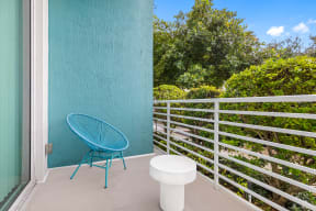 a patio with a blue chair and a stool on a balcony