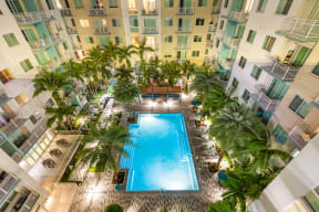 an overhead view of an apartment building with a pool and palm trees