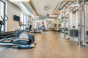a gym with cardio equipment and weights on the floor