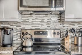a kitchen with stainless steel appliances and a tea kettle on the stove
