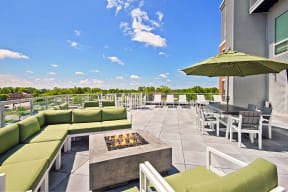 a patio with green couches and chairs and a fire pit