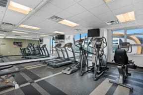 a gym with treadmills and other exercise equipment in a room with windows