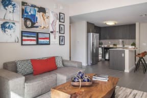 a living room with a couch and a coffee table and a kitchen