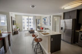 a kitchen and living room with stainless steel appliances and an island with stools