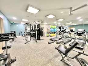 A gym with a variety of equipment including treadmills, weights, and exercise machines.