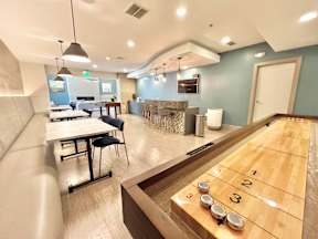 A shuffleboard court is in the middle of a room with a blue wall.