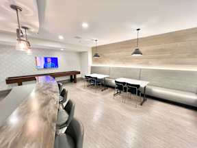 A conference room with a long table and chairs, a television screen, and a stone wall.