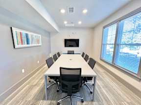 A conference room with a long table and chairs.