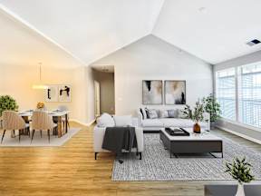 A modern living room with a grey sofa and a wooden dining table.