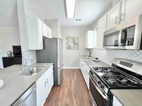 A modern kitchen with white cabinets and stainless steel appliances.