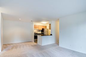 A kitchen area with a counter and cabinets is visible through a doorway.