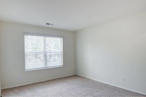 A room with a window and carpeted floor.