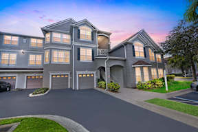 A large, modern house with a curved driveway and multiple garages.