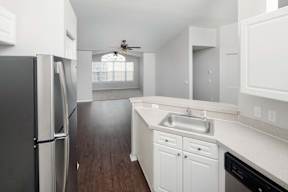 A kitchen with a black refrigerator and white cabinets.