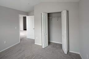 A room with a carpeted floor and two open doors.