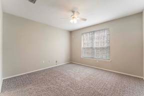 A room with a ceiling fan and a window with blinds.